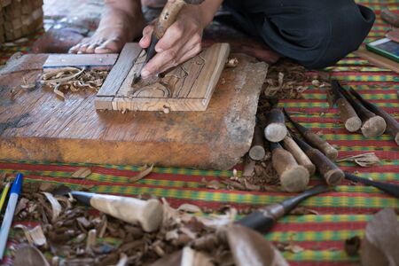 Chiang Mai, Thailand - July 1, 2017: craftsman use a gouge to carve traditional bas-relief on wood at Lanna Expo 2017 in Chiang Mai, Thailand on July 1, 2017.の写真素材