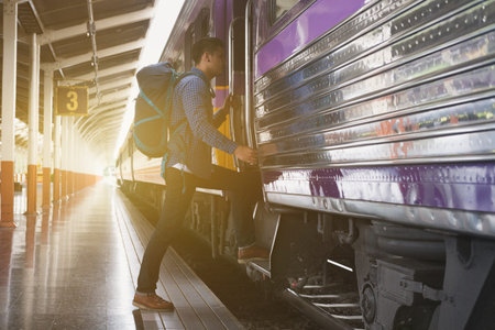 feet of young man, tourist or traveler stepping up to the train on railway at train station. Travel, journey, trip conceptの写真素材