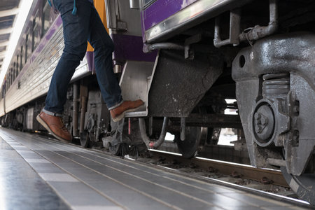 feet of young man, tourist or traveler stepping up to the train on railway at train station. Travel,...