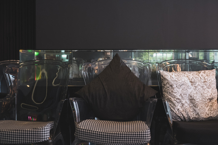 transparent plastic chair with black and white cushion and fabric pillow in living roomの写真素材
