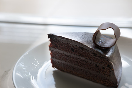 piece of tasty dark chocolate cake on white plate. sliced delicious cocoa bakery dessert.の写真素材