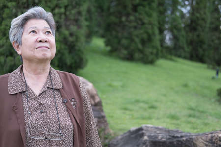 asian elder woman standing in garden. elderly senior female resting and relaxing in parkの写真素材