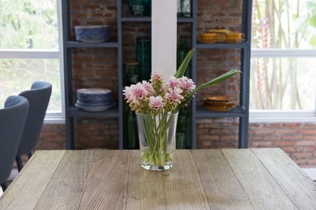 pink siam tulip flower in vase on wood table near window with garden view. decoration and interiorの写真素材