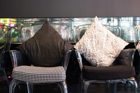transparent plastic chair with black and white cushion and fabric pillow in living roomの写真素材