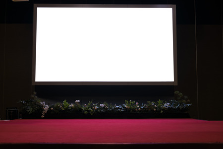 blank projector screen on stage with red carpet in conference hall.の写真素材