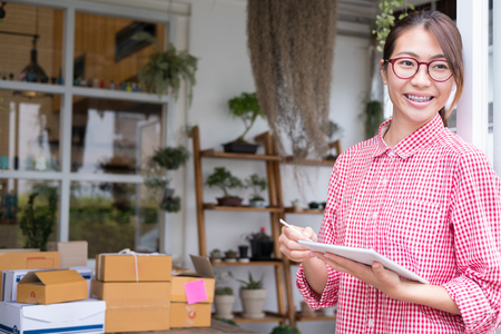 young start up small business owner working with digital tablet at workplace. freelance woman entrepreneur SME seller check product order to prepare for delivery to customers.  Online selling, internet marketing, e-commerce, shipping conceptの写真素材
