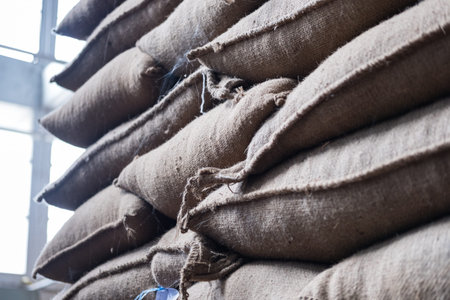 old hemp sacks containing coffee bean in warehouse. stacked sacks in storehouse.
