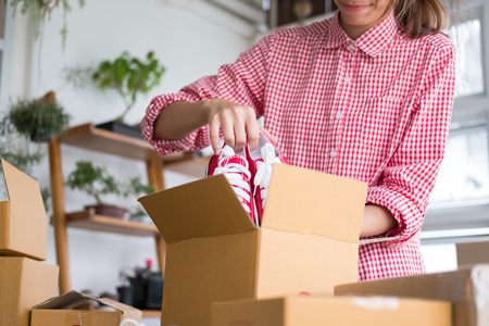 young start up small business owner packing shoes in the box at workplace. freelance woman entrepreneur SME seller prepare product for packaging process at home.  Online selling, internet marketing, e-commerce conceptの写真素材