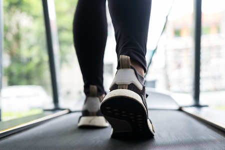 young woman execute exercise in fitness center. female athlete walking on treadmill in gym. sporty asian girl working out in health club.の写真素材