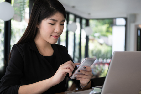 businesswoman use mobile phone at workplace. young woman texting message on smart phone at office. female freelancer use cellphone for online network connection at cafe coffee shop.の写真素材