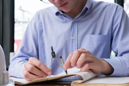 architect hand holding drawing compass working on construction plan at office. engineer inspect...