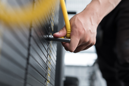young man execute exercise with pull down machine in fitness center. male athlete select weight for training in gym. sporty asian guy working out in health club.の写真素材