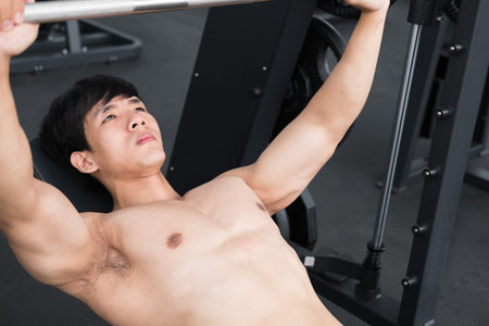 young man execute exercise with weightlifting machine in fitness center. male athlete pump up muscle...