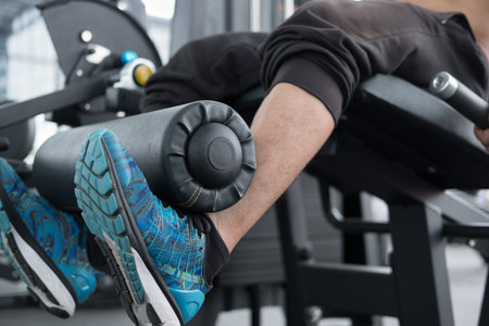 young man execute exercise with weightlifting machine in fitness center. male athlete pump up leg...