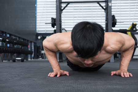 young muscle man doing push ups in gym. bodybuilder male working out in fitness center. athlete doing exercises in health club. strength, sport, training, healthy lifestyle conceptの写真素材