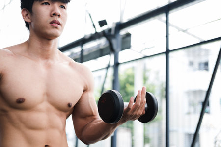 young man lift dumbbell in gym. bodybuilder male working out in fitness center. sport guy doing...