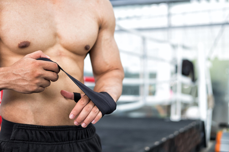young male fighter wear bandages on fist. muscular man bind bandage on hand before training. sportsman prepare for boxing practice.の写真素材