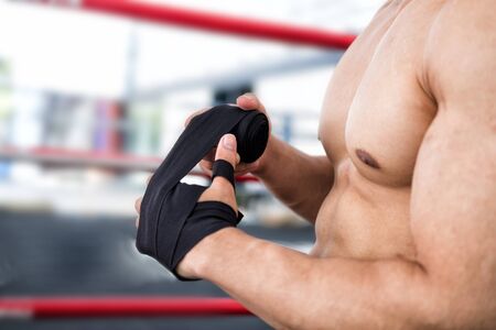 young male fighter wear bandages on fist. muscular man bind bandage on hand before training. sportsman prepare for boxing practice.の写真素材