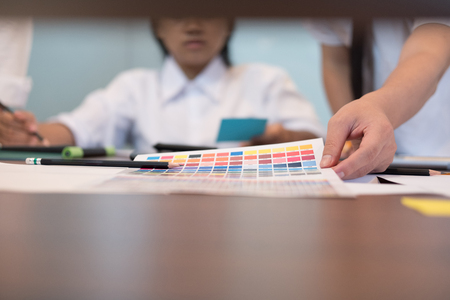 hand of graphic or interior designer choosing a colour from color swatch sampler or catalogue palette guideの写真素材