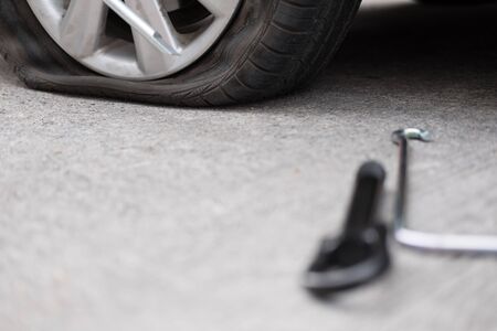 Car tire leak because of nail pounding. flat tyre on road. Flatten punctured auto wheelの写真素材