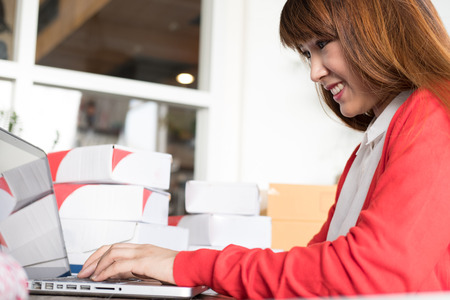 start up small business owner check product order with computer at workplace. freelance woman seller prepare parcel box for deliver to customer.  Online selling, e-commerce, shipping conceptの写真素材