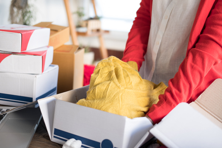 start up small business owner packing cloth in the box at workplace. freelance woman seller prepare product for packaging process at shop.  Online selling, e-commerce conceptの写真素材