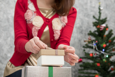 portrait of asian woman sit near christmas tree at home. girl with gift present box. christmas holiday. merry xmas celebration. season's greetingsの写真素材