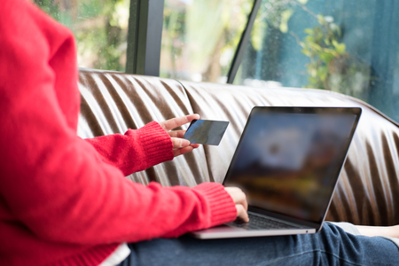 young woman holding credit card for online shopping. female adult use computer to make payment on internet at home.の写真素材