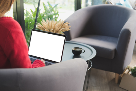 young woman wearing red sweater typing on computer at home.の写真素材