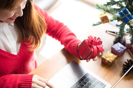 asian woman use computer at home. girl with gift present box for christmas holiday. merry xmas, new year celebration. season greetingsの写真素材