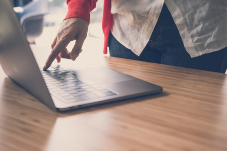 young start up woman wearing red cardigan press on computer at home. freelance female adult working...