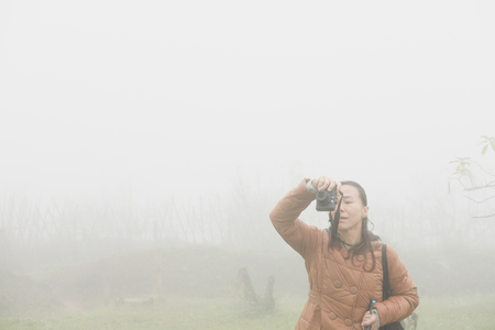 Woman take photo in mist and fog. tourist take picture in forest.の写真素材