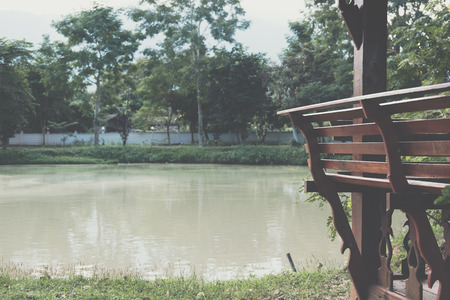 wood bench in gazebo for resting at waterside of pond in parkの写真素材