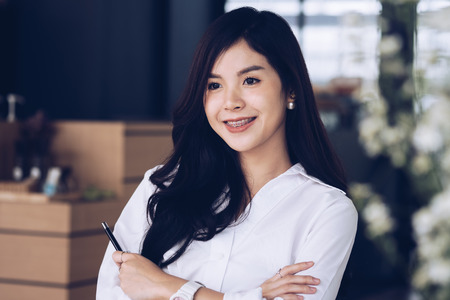 confident businesswoman standing with arms crossed at office. successful young female entrepreneur woman smiling at workplace. working, business conceptの写真素材
