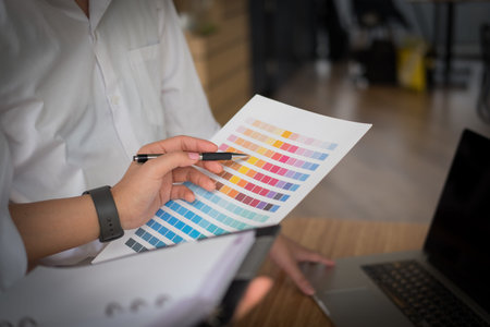 graphic or interior designer choosing color from swatch sample or catalogue palette guide at...