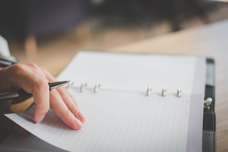 man's hand holding ballpoint pen at office. student learning lesson with notebook. business,...