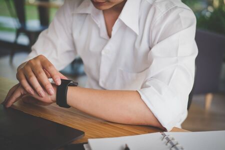 busy businessman look at smartwatch at workplace. startup man check time on wristwatch.  young male entrepreneur working at office.の写真素材