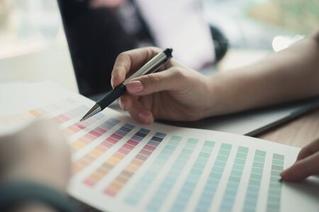 graphic or interior designer choosing color from swatch sample or catalogue palette guide at workplace. artist discussing design & idea at office. business people brainstorming for new creativity project. teamwork, partnership conceptの写真素材