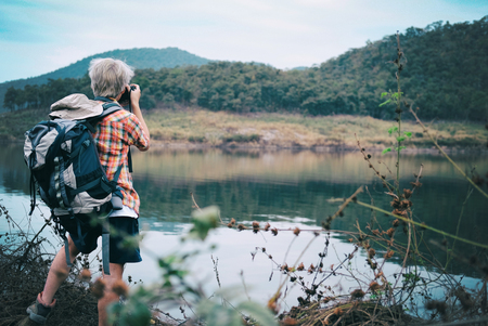 traveler hiker man with backpack hiking near lake. tourist backpacker take photo in forest. travel lifestyle & summer vacation conceptの写真素材