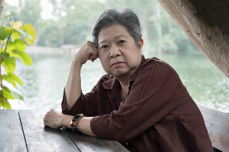 asian elder woman resting in garden. elderly female relaxing in park. senior leisure lifestyle outdoors.の写真素材