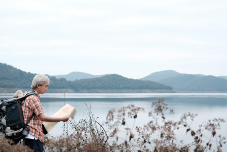 traveler hiker man with backpack hiking near lake. tourist backpacker with map relaxing in forest. travel lifestyle & summer vacation conceptの写真素材