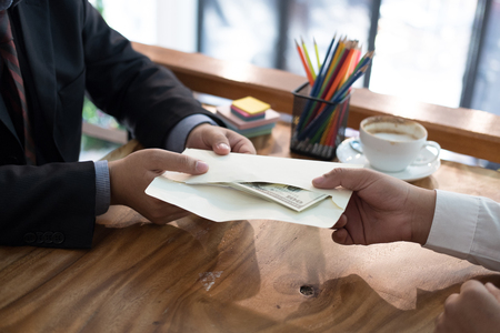 Businessman receiving envelope with money banknote. hand giving cash banknote to man - bribery, corruption, venality conceptの写真素材