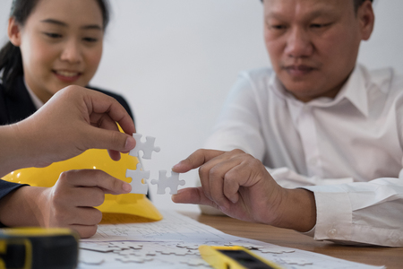 business people assembling piece of puzzle together. co worker team solving problem. unity teamwork collaboration connection conceptの写真素材