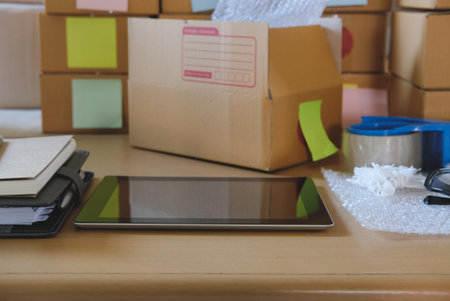 tablet, packing accessories at workplace of startup small business owner, cardboard parcel box for...