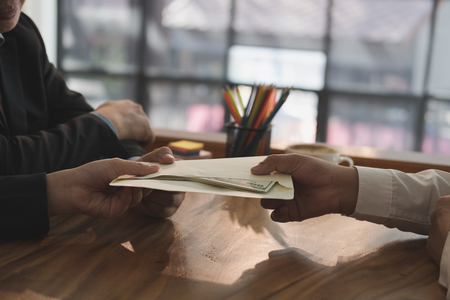 Businessman receiving envelope with money banknote. hand giving cash banknote to man - bribery, corruption, venality conceptの写真素材