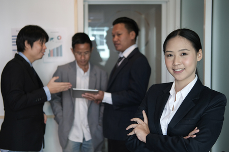 asian businesswoman smiling at camera while colleagues have meeting at office. businessman working with co worker team at workplaceの写真素材