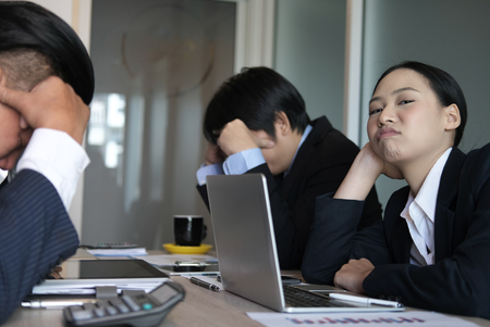 bored businesswoman lean head on hand at meeting. unhappy businessman at conference. sad colleagues at office. business teamwork crisisの写真素材