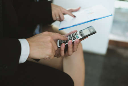 business adviser working with calculator & financial plan report at office. accountant doing accounting & calculating tax, revenue & budget. bookkeeper making calculation. finance and economy conceptの写真素材