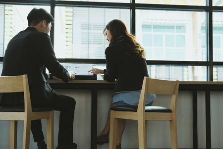 young business people having a meeting. businessman & businesswoman working with financial plan report at cafe. startup man & freelance woman discussing market data at coffee shop. discussion, teamwork, collaboration, corporate concept.の写真素材