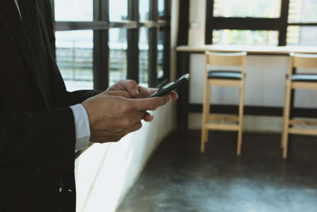 young businessman holding smartphone & using app at office. man texting message at workplace. social network communication, wireless connection, lifestyle conceptの写真素材